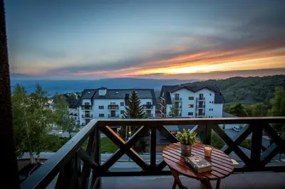 a table on a balcony with a sunset in the background at View - Apartment at Kopaonik in Kopaonik