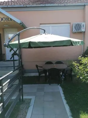 a table and chairs under an umbrella in a yard at Smestaj Pandora Sobe sa kupatilom in Jagodina