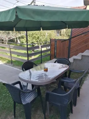 a table and chairs with a green umbrella at Smestaj Pandora Sobe sa kupatilom in Jagodina