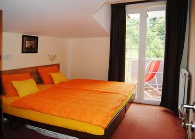 a bedroom with a bed with an orange blanket on it at Vila Paradi in Vrnjačka Banja