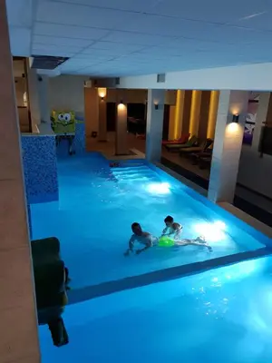 two children playing in a swimming pool with blue lights at Milmari, Resort, Premier Apartman A52 & Parking garage FREE in Kopaonik