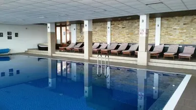 a swimming pool in a building with chairs in it at A1 Premier Milmari resort in Kopaonik
