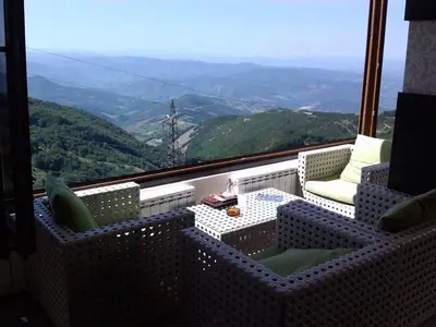 a balcony with two chairs and a table with a view at A1 Premier Milmari resort in Kopaonik