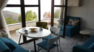 a living room with a table and chairs and a large window at Apartman D52 Dvori in Kopaonik