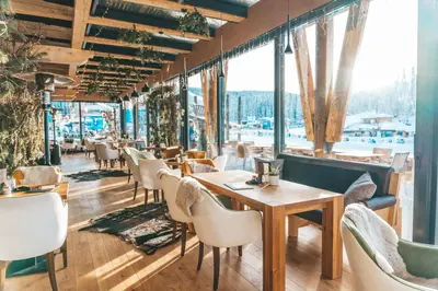 a restaurant with tables and chairs and windows at Gorski Hotel & Spa in Kopaonik