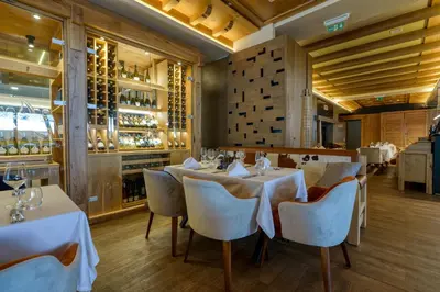 a restaurant with white tables and chairs and wine bottles at Gorski Hotel & Spa in Kopaonik