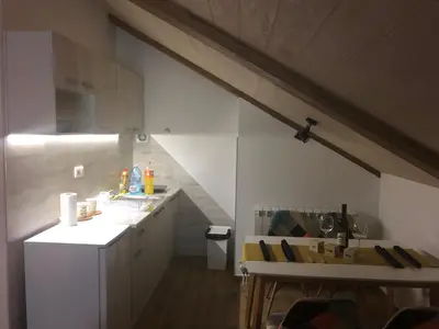 an attic kitchen with white cabinets and a staircase at Iznad oblaka A9 in Kopaonik