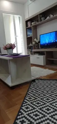 a living room with a table and a tv at Apartman Harmonija Vrnjačka Banja in Vrnjačka Banja