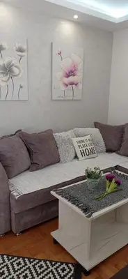 a couch in a living room with three flowers on the wall at Apartman Harmonija Vrnjačka Banja in Vrnjačka Banja