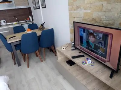 a living room with a television and a table with blue chairs at Apartman Šilja L22 Milmari Kopaonik in Kopaonik