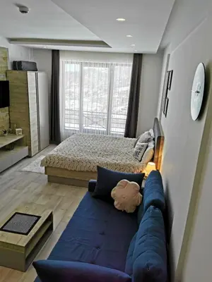a bedroom with a blue couch in front of a bed at Apartman Šilja L22 Milmari Kopaonik in Kopaonik