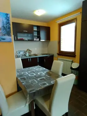 a kitchen with a table with white chairs and a counter at Apartman Vila Natasa in Kopaonik