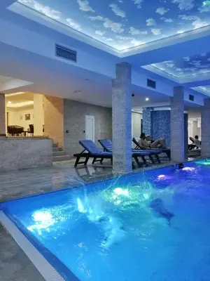 a large blue swimming pool in a room with a table at Kophill L36 Milmari in Kopaonik