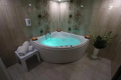 a bath tub filled with blue water in a bathroom at Garni Hotel Laguna Lux in Niš