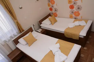 two beds in a small room with towels at Garni Hotel Laguna Lux in Niš