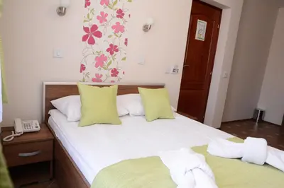 a bedroom with a bed with yellow pillows and a phone at Garni Hotel Laguna Lux in Niš