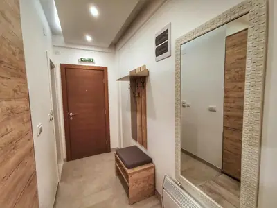 a hallway with a mirror and a wooden door at Apartman Pahulja - Milmari in Kopaonik