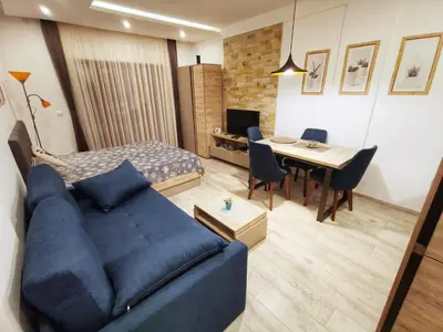 a living room with a blue couch and a bedroom at Apartman Pahulja - Milmari in Kopaonik