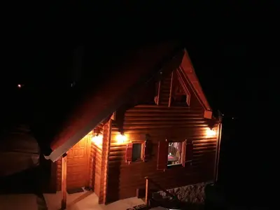 a cabin with lights on the side of it at night at Vila Jelena in Crni Vrh