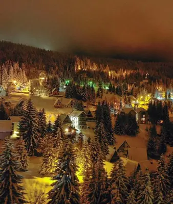 a town covered in snow at night with christmas lights at Villa Polaris in Kopaonik