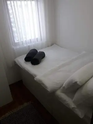 a bed with two pillows on it with a window at Apartman Marija, Vila Suri in Kopaonik