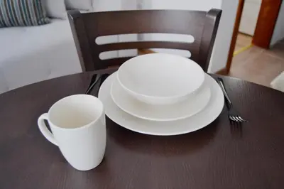 two white plates and a cup on a table at Apartman Marija, Vila Suri in Kopaonik
