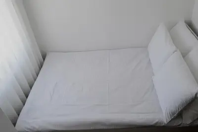 a small bed with white sheets and pillows at Apartman Marija, Vila Suri in Kopaonik