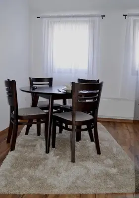 a dining room table with four chairs and a rug at Apartman Marija, Vila Suri in Kopaonik