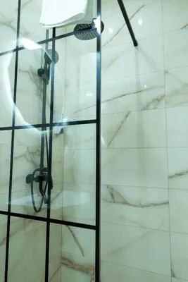 a shower in a bathroom with white marble at Apartmani Central & Free parking in Vrnjačka Banja