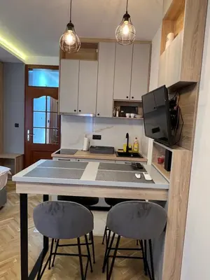 a kitchen with a counter with two stools and a table at Apartmani Central & Free parking in Vrnjačka Banja