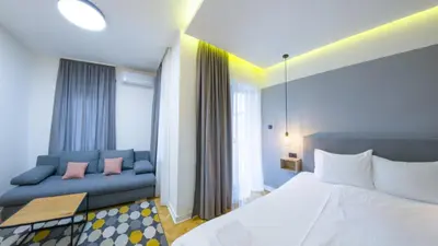 a bedroom with a bed and a blue couch at Apartmani Central & Free parking in Vrnjačka Banja