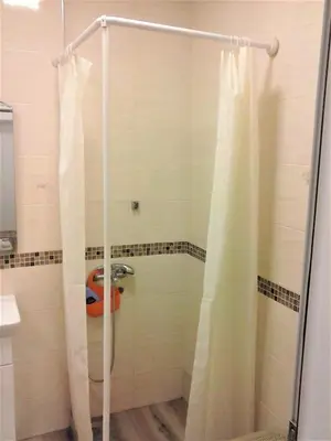 a shower with a white shower curtain in a bathroom at Apartman Veljic in Niš