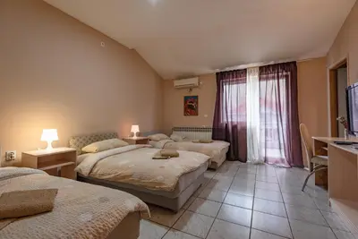 a bedroom with three beds and a desk and a television at B&B Bebinac in Leskovac