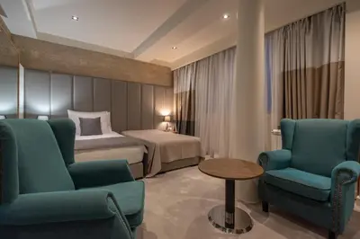 a hotel room with a bed and two chairs and a table at Hotel ABC in Leskovac