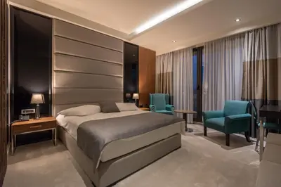 a bedroom with a bed and two blue chairs at Hotel ABC in Leskovac