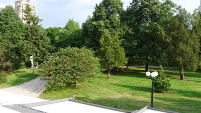 a park with a giraffe in the grass and trees at Hotel ABC in Leskovac