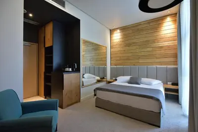 a bedroom with a bed and a couch and a chair at Hotel ABC in Leskovac