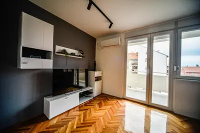 a living room with a television and a large window at goltepirot in Pirot
