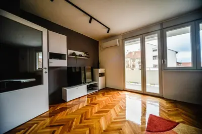 a living room with a wooden floor and a large window at goltepirot in Pirot