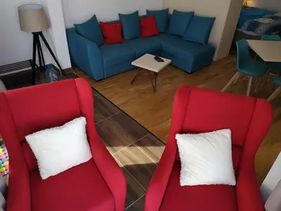 two red chairs and a blue couch in a living room at Apartman D11 Dvori in Kopaonik