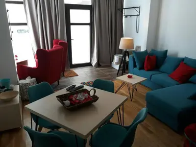 a living room with a blue couch and a table and chairs at Apartman D11 Dvori in Kopaonik
