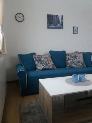 a living room with a blue couch and a table at Apartman Jana do Kraljevih cardaka in Kopaonik