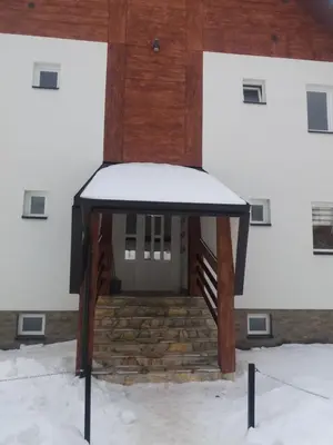 a building with a snow covered door and stairs at Apartman Jana do Kraljevih cardaka in Kopaonik