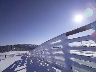 a fence covered in snow next to a ski slope at Ljubica in Brzeće