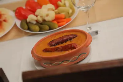 a bowl of food on a table with a plate of vegetables at BAJKA in Crni Vrh