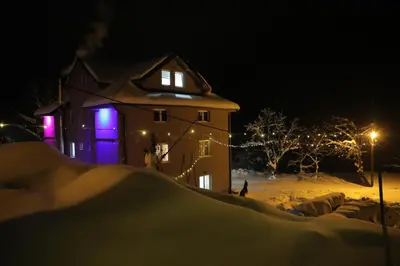 a house with lights on in the snow at night at BAJKA in Crni Vrh