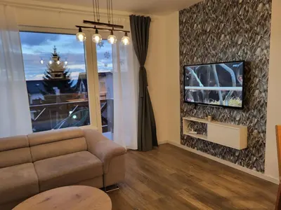 a living room with a couch and a tv on a wall at Apartman Jovanovic Kopaonik in Kopaonik