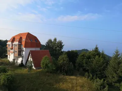a house with a red roof on top of a hill at Iznad Oblaka Apartman 8 in Kopaonik