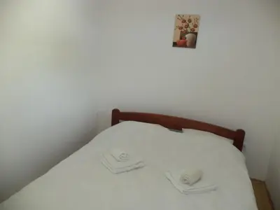 a bed with white sheets and two towels on it at Apartments 1A JollyKop in Kopaonik