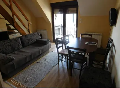 a living room with a couch and a table and chairs at Apartments 1A JollyKop in Kopaonik